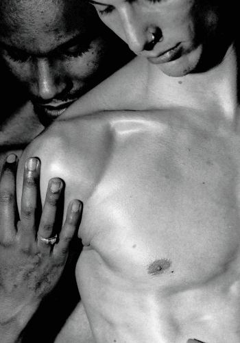 A man being tenderly embraced from behind by another man.